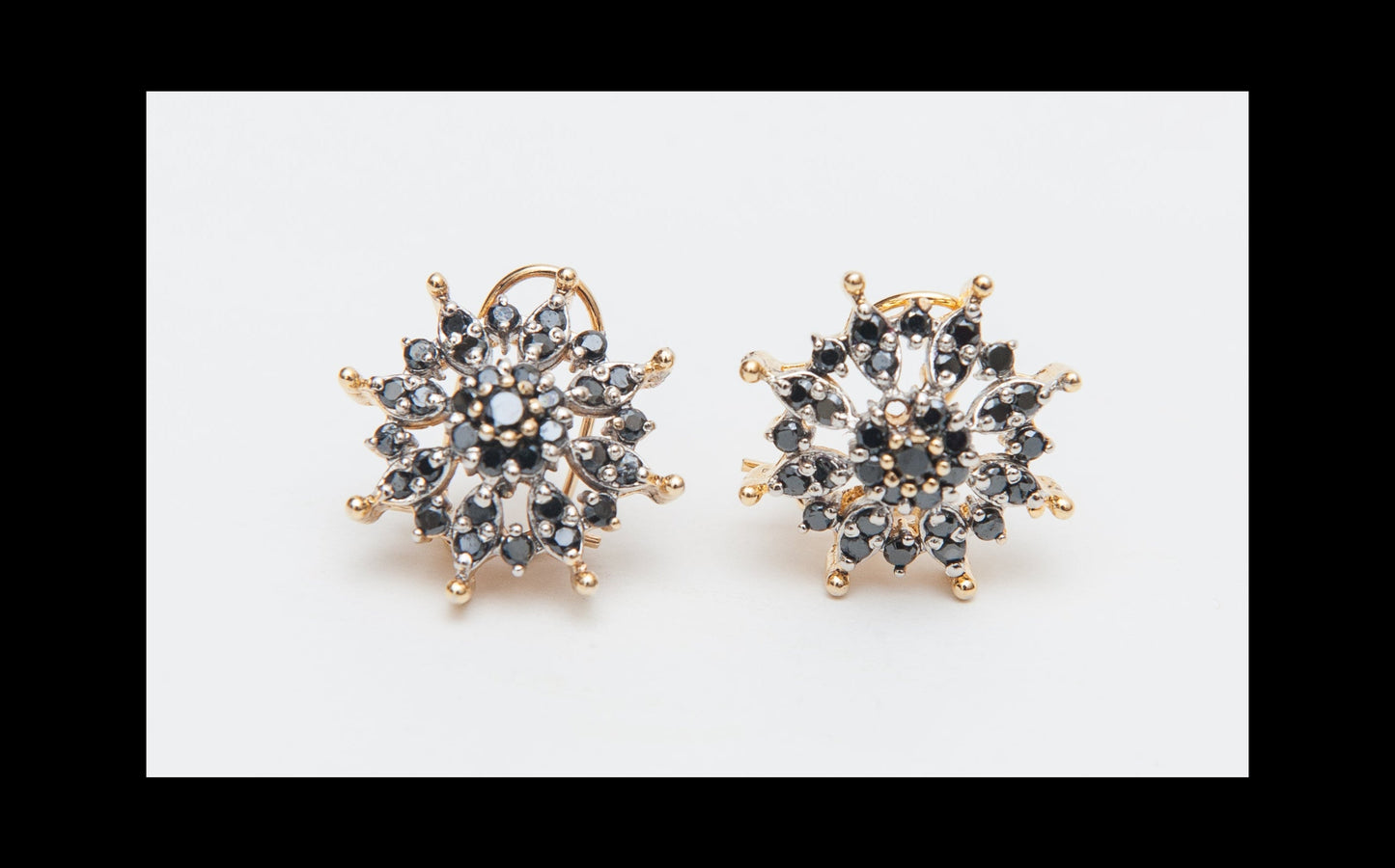 Pair of gold and black stud earrings on a white background