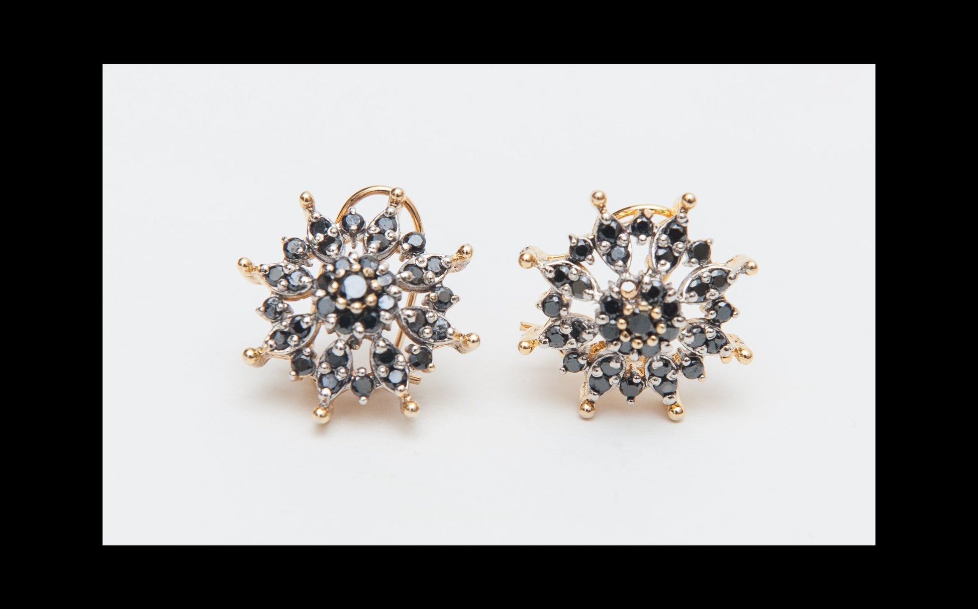 Pair of gold and black stud earrings on a white background