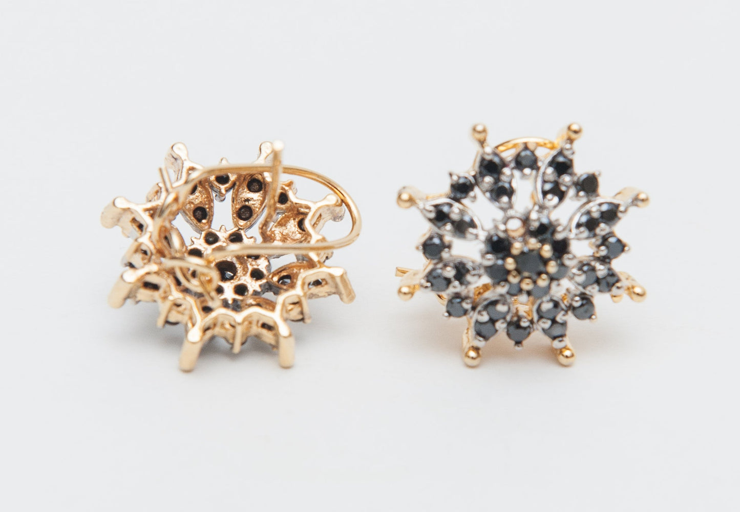 Pair of gold and black earrings on a light gray background