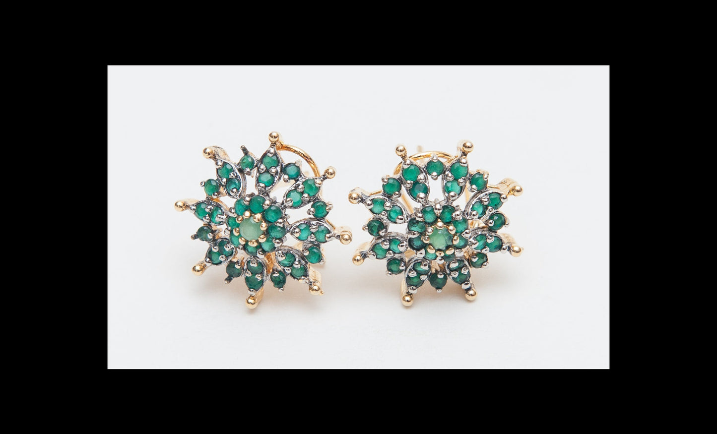 Pair of gold earrings with green gemstones on a white background