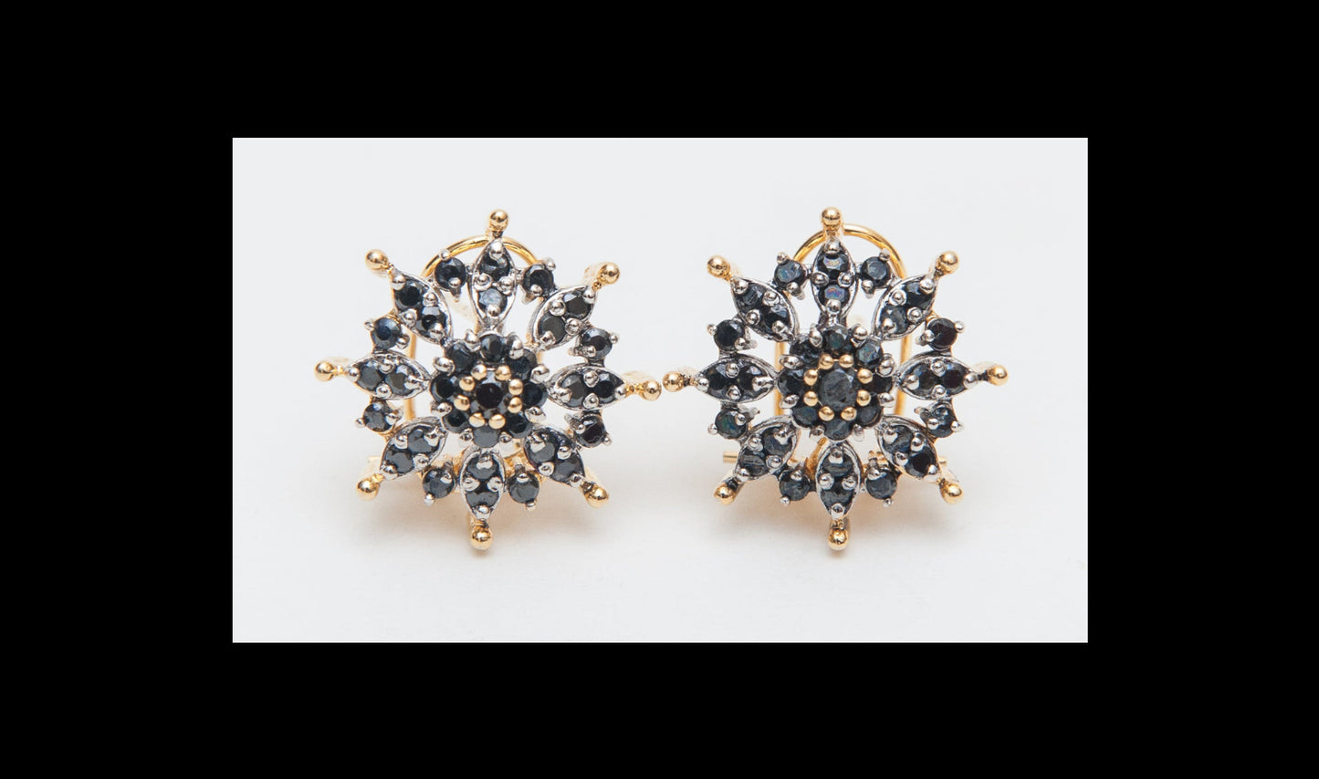 Gold and black snowflake-shaped earrings on a white background