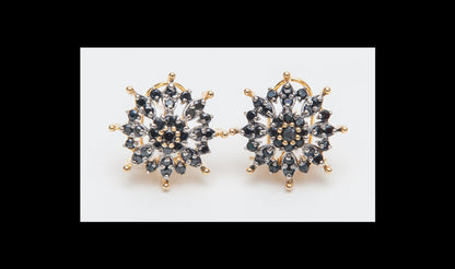 Gold and black snowflake-shaped earrings on a white background