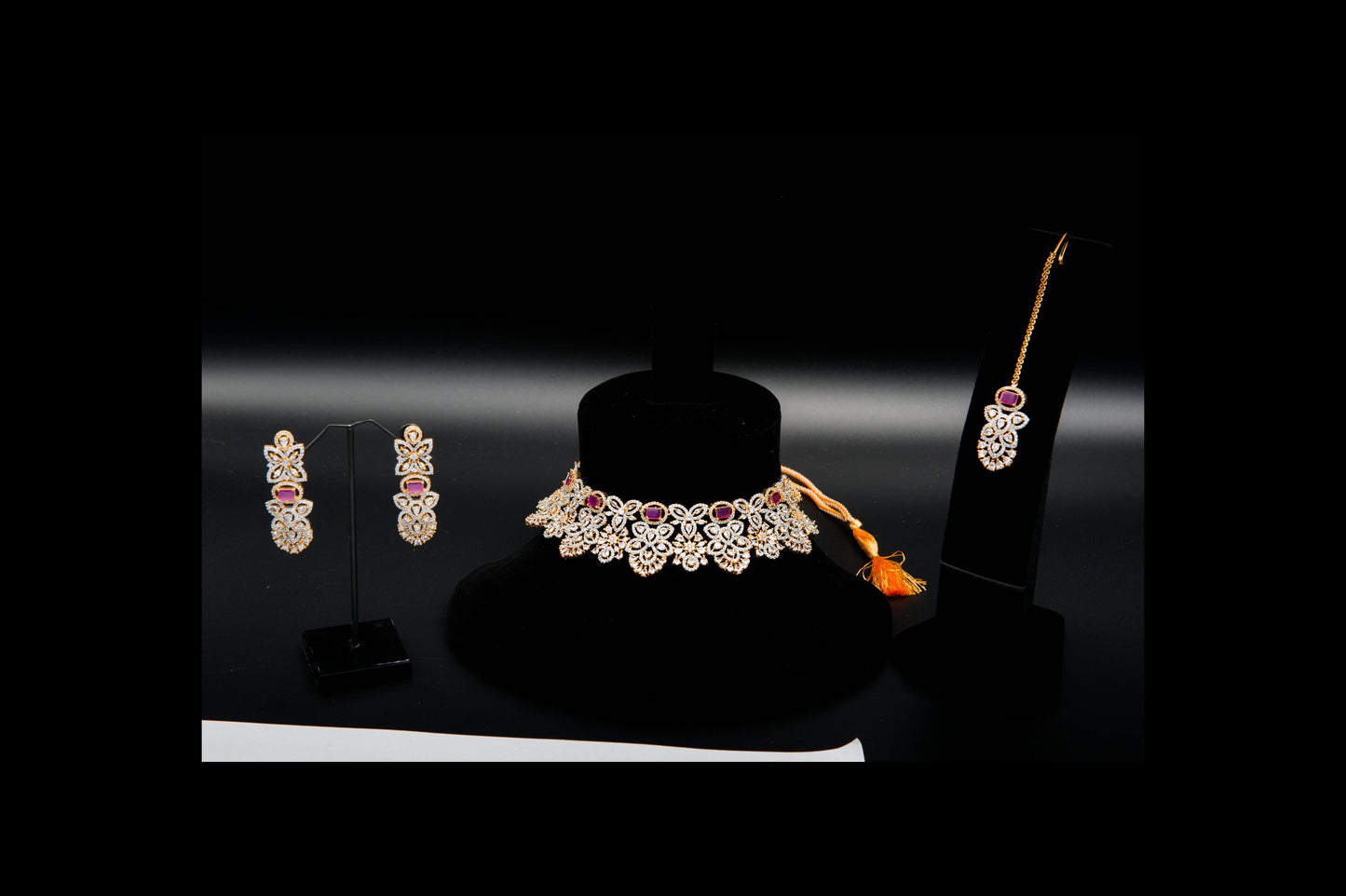 Jewelry set including necklace and earrings on black stands with a dark background