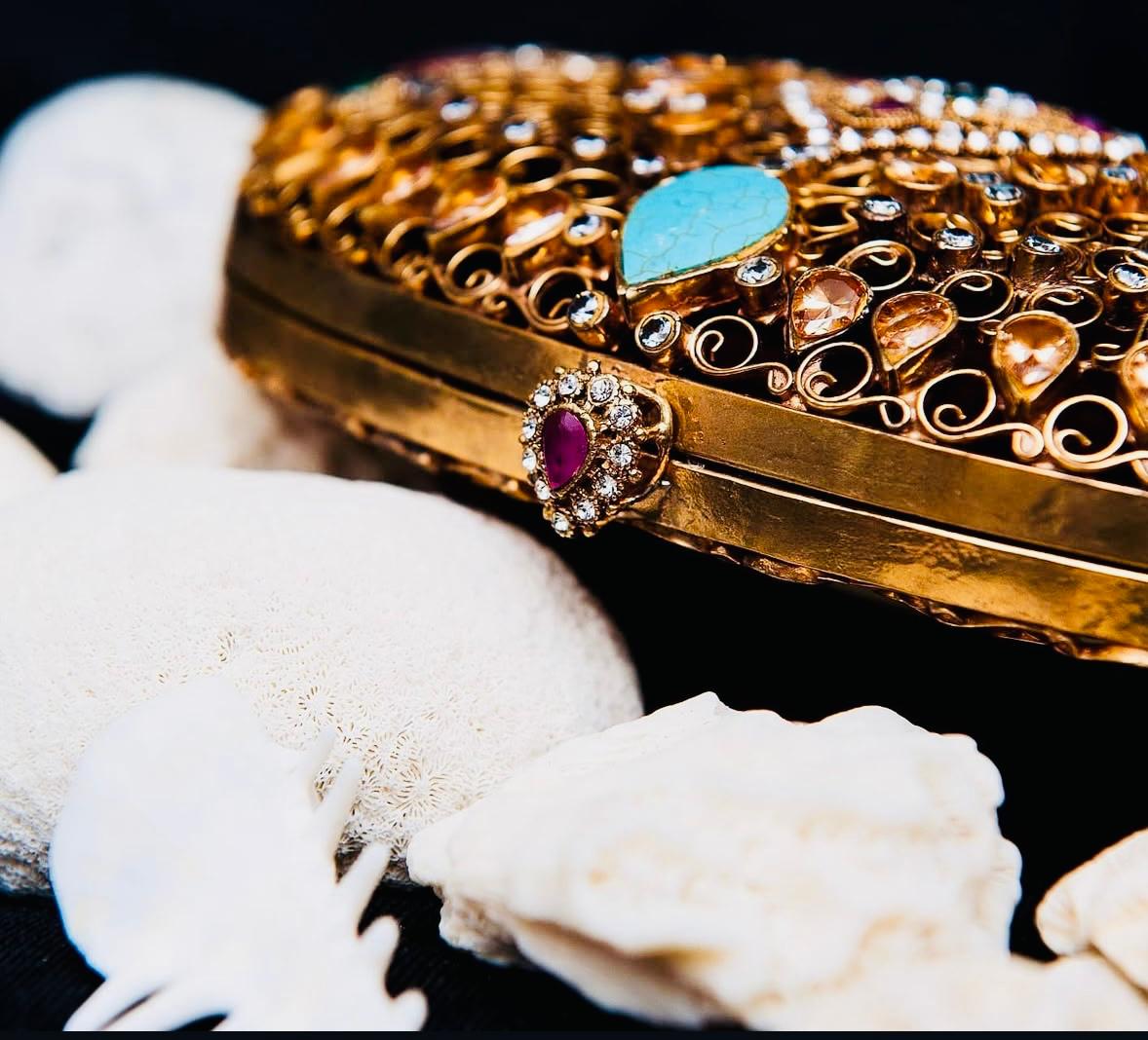 Gold decorative item with gemstones on a white coral background